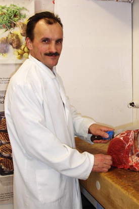Luis Franco cutting meat at the counter of Battersea Family Butchers