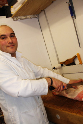 Ricardo Perestrelo preparing meat at the counter of Battersea Family Butchers